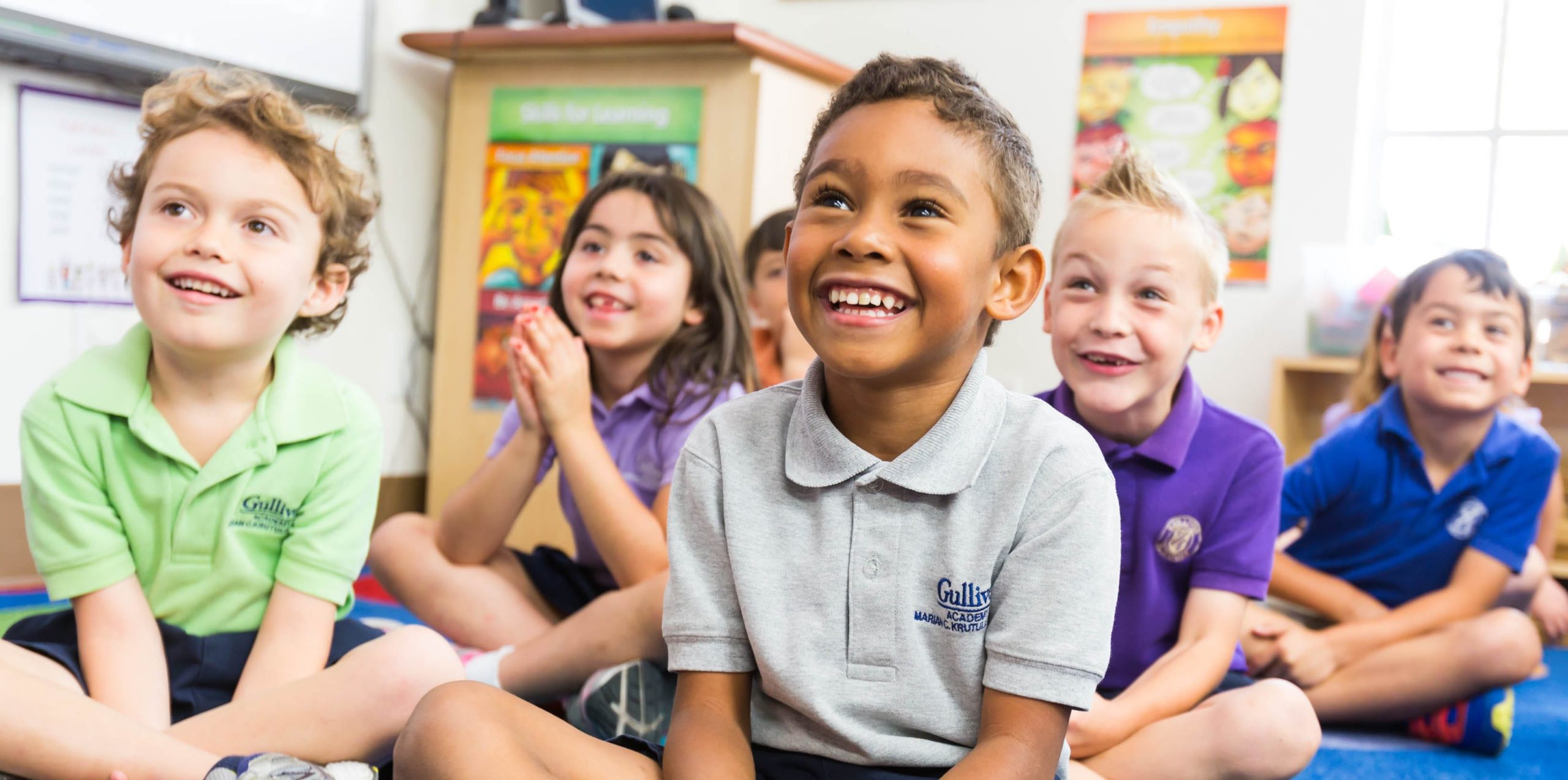 Primary school kids sitting on the floor smiling